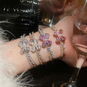 Close-up of layered open bracelets with zircon butterfly and flower charms on model