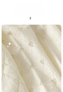 Close-up of white knit fabric with diamond patterns and heart-shaped hollow-out details