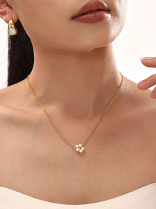 Close-up of elegant double-layered gold flower necklace with white pearl petal details