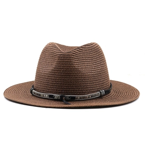 Detailed texture of brown straw fedora featuring a vintage belt with metal cross and feather