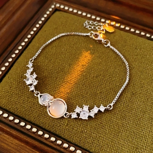 Detail of silver bow bracelet featuring a moonstone gourd pendant and sparkling crystals