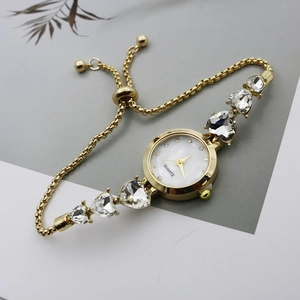 Close-up of gold chain watch band featuring heart-shaped rhinestones and sliding clasp