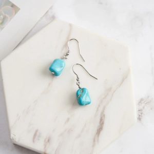 Detailed view of turquoise silver drop earrings on a white marble hexagonal tray