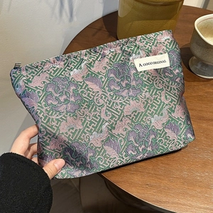 Detail view of brocade makeup bag featuring traditional green and purple dragon patterns
