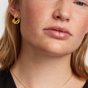 Detail shot of a model wearing 18K gold plated stainless steel chain link hoop earrings