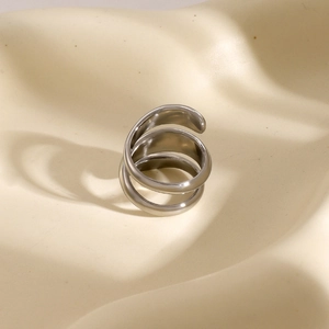 Macro detail of silver-tone stainless steel triple spiral ring on a minimalist display