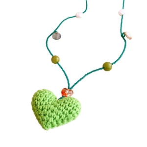 Collier fait main avec pendentif cœur au crochet vert, perles et billes sur fond blanc