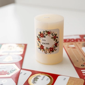 Cylindrical scented candle with elegant Christmas wreath labels for gift wrapping
