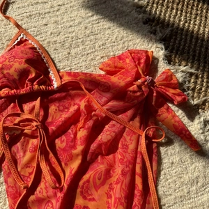 Vue détaillée du haut de bikini à motif paisley et paréo en résille avec bordure dentelle
