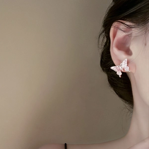 Detailed close-up of a pink enamel butterfly earring on model with silver metal base