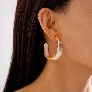Macro view of C-shaped hoop earrings with colorful hand-woven gradient thread on model