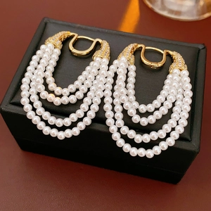 Close-up of vintage pearl earrings with gold metal and zircon accents on black jewelry box