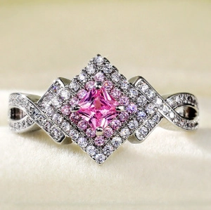 Macro shot of silver ring with pink princess cut stone and infinity twist diamond band