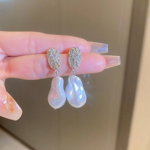 Detailed close-up of wrinkled silver earrings featuring baroque pearls and metallic texture