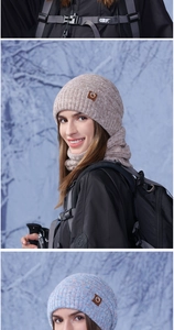 Detail of chunky knit winter hat and neck warmer with logo leather patch on beige fabric