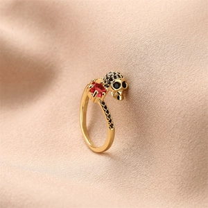 Detail of skull ring with black pavé stones and a red crystal on a gold-plated band