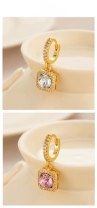 Detailed close-up of square zircon drop earrings with pavé crystals on cream ceramic