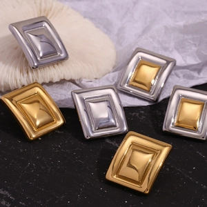 Detailed shot of geometric rectangular earrings in gold and silver on a minimalist display