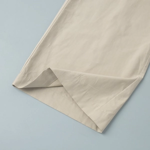 Close-up of beige casual wide-leg pants hem showing neat stitching and smooth fabric texture