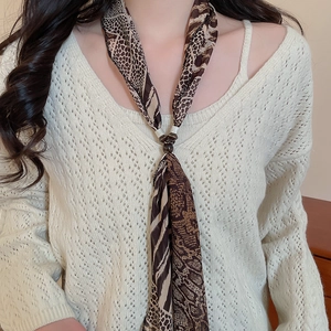 Close-up of leopard print chiffon scarf necklace styled on a cream knit sweater