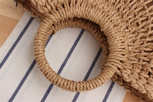 Detail of the woven paper rope bag showing round handle, crochet texture, and fabric lining