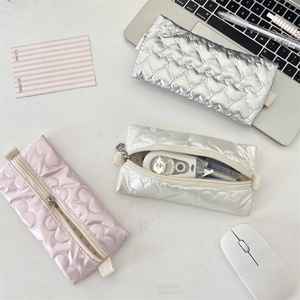 Detailed view of quilted heart pencil case holding pens on a workspace desk
