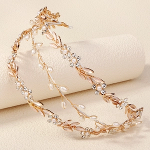 Detail of gold bridal headband with white pearls and crystal flower leaves on a beige stand