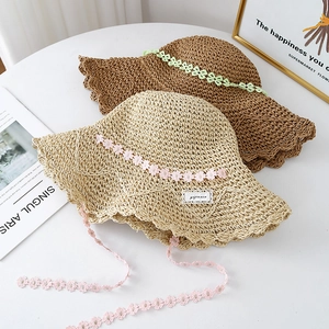 Handwoven straw sun hat with floral lace trim and wide wavy brim for beach vacation