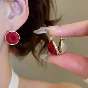 Close-up of reversible round earrings with red velvet and white pearl in gold setting