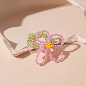 Close-up of handmade beaded flower ring with pink glass petals and yellow center