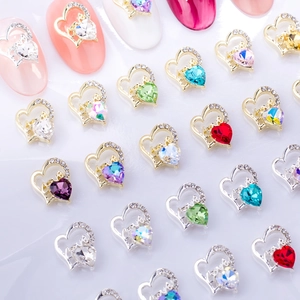 Détail macro de breloques à ongles en forme de cœur avec strass et lettrage Love gravé
