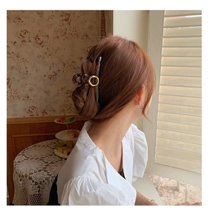 Elegant tortoiseshell resin hair claw clip with golden metal ring on model's hair