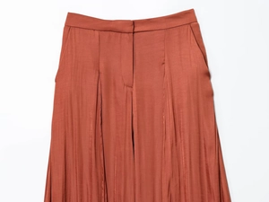 Detailopname van glanzende satijnen broek in karamel met focus op de taille en de stof