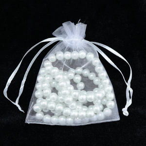 Detailed view of white organza drawstring gift bag filled with shiny imitation pearls
