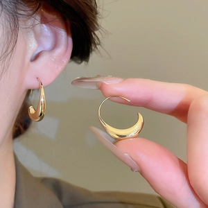 Detailed view of 14k gold plated chunky C-shape hoop earrings on ear and fingertips