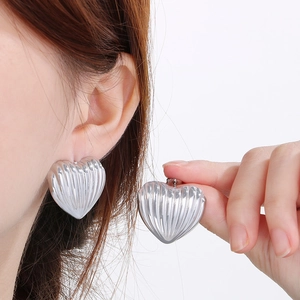 Chunky silver heart earrings with vertical striped texture shown on model in main view