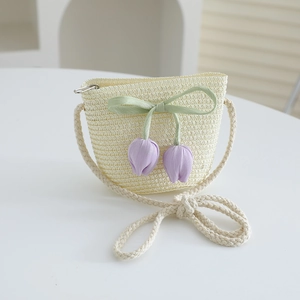 Close-up of beige woven straw bag with green bow and purple tulip floral charms