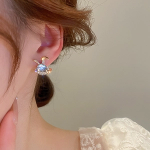Detail showing a star-shaped rabbit earring with light blue crystal on a model's ear