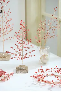 Close-up of red berry Christmas ornaments with festive gold glitter on branches