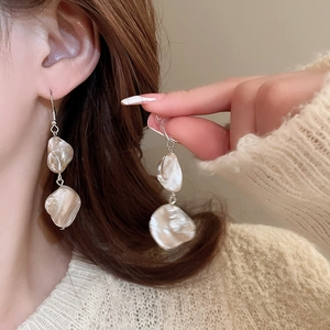Dettaglio di orecchini con perle barocche e ganci in argento indossati da una modella
