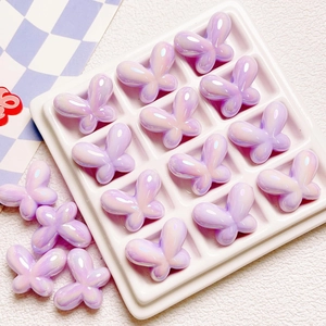 Macro shot of iridescent purple bow-shaped resin beads for DIY jewelry and phone chains