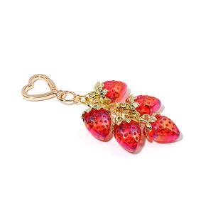 Detail of red strawberry keychain with five resin fruits and a gold heart clasp
