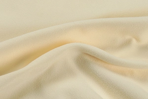 Close-up of soft light beige knitted fabric with warm velvet texture and premium fibers