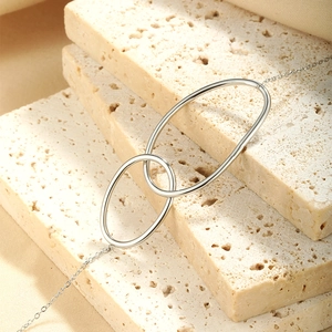 Detail of silver double circle interlocking pendant on textured beige stone background