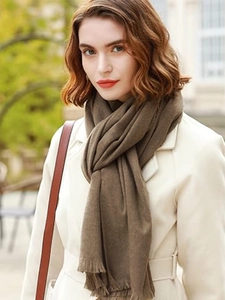 Close-up of a soft brown cashmere scarf with classic tassels on an outdoor model