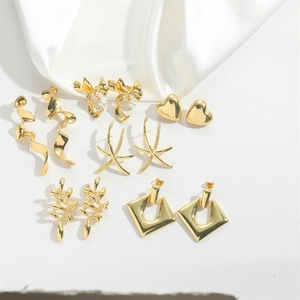Detailed collection of gold heart and geometric earrings displayed on white silk fabric