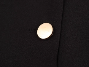 Macro shot of gold metal button detail on black low-rise hot pants for women