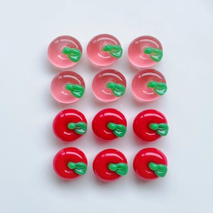 Flat lay of 12 mini resin apple charms in translucent pink and opaque red on white