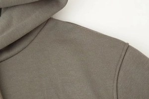 Detailed close-up showing the taupe knitted fabric texture and shoulder seam stitching