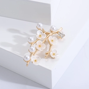Close-up of golden flower brooch with white petals, pearls and crystals on white blocks